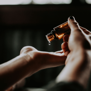 person holding amber glass of essential oils