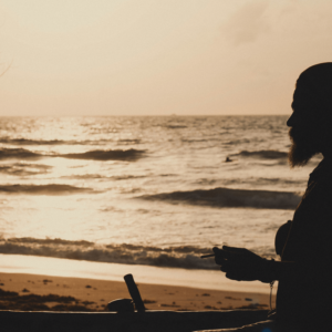 man with a beard smoking on the beach