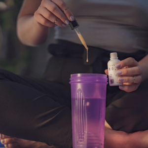 person adding a tincture into a purple cup