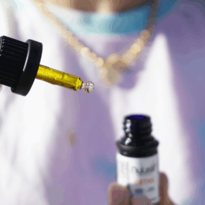 person holding dropper containing gold liquid