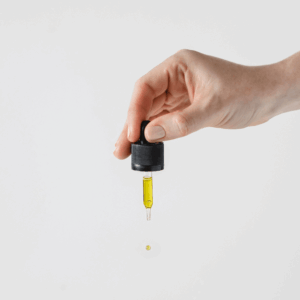hand holding dropper of gold oil