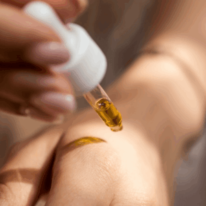 person applying gold CBD oil to hand