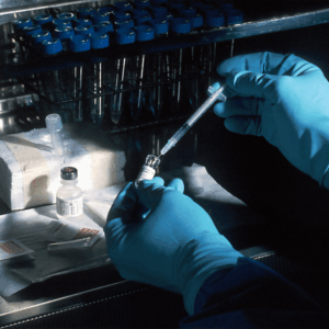person sticking syringe in vial