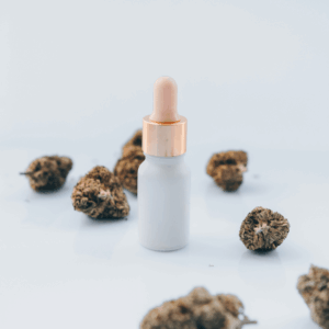 white tincture bottle and cannabis flower
