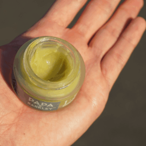 person holding yellow/green CBD balm